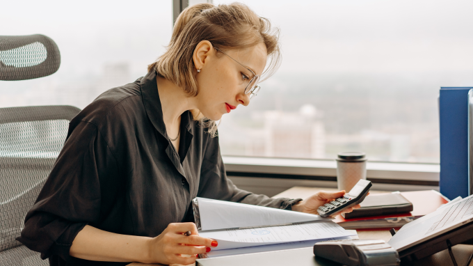 Woman reviewing paperwork with a calculator