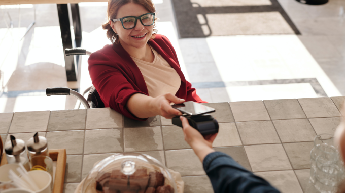 Woman using her phone to pay on a card machine