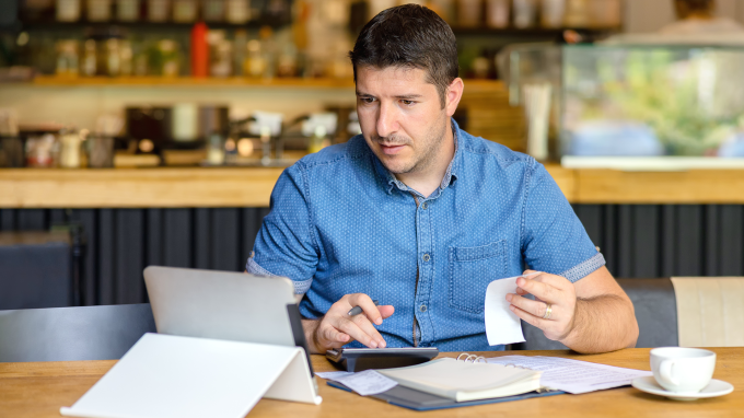 Person checking their accounts with a calculator and laptop