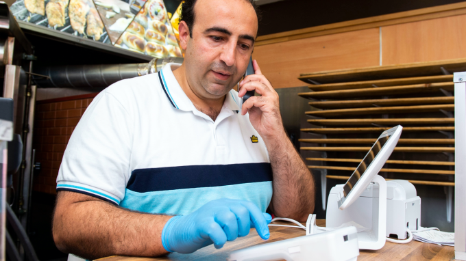 A person in a fast food restaurant using a phone to take a payment